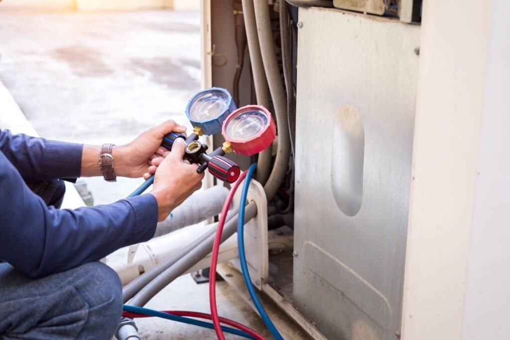 heat pump servicing, two hands holding pipes and gauge